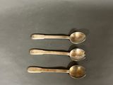 three silver spoons sitting on top of a table next to each other