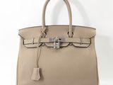 un sac à main en cuir beige muni d'un fermoir métallique sur la poignée