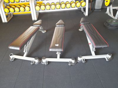 une salle de sport avec une rangée de bancs et une rangée d'haltères