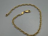 un bracelet en chaîne d'or muni d'un fermoir, posé sur une surface grise