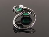 a close up of a ring with green stones on a black surface