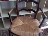 une chaise en bois avec une assise tressée, placée devant une bibliothèque