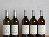 six bottles of wine are lined up on a wooden table