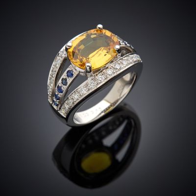 une bague sertie d'un saphir jaune et de diamants, posée sur un fond noir