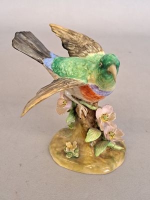 a figurine of a bird sitting on a tree branch