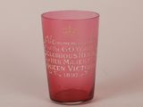 un verre rose portant une inscription, posé sur une surface blanche