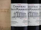 three bottles of red wine are lined up on a shelf