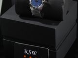 the watch is sitting on top of a black box next to a business card