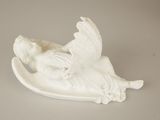 a white figurine of an angel laying on a plate