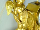 a gold clock with an angel on it on a table