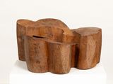 a wooden bench made out of logs on a white pedestal
