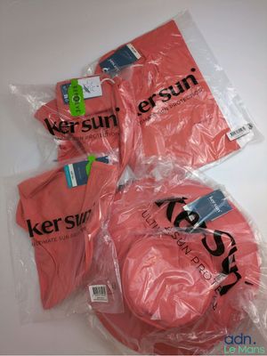 trois t-shirts roses sont emballés dans des sacs en plastique sur une table