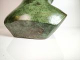 a green vase that is sitting on a white table