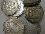 quatre types différents de pièces d'argent sur une surface blanche