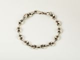 a close up of a silver chain bracelet on a white surface