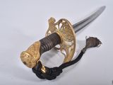 a sword with a gold handle on a white surface
