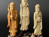 three chinese carved figurines of men and women on a black surface