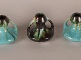 three small vases are lined up on a white surface
