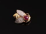gros plan d'une bague en or avec un rubis et des diamants