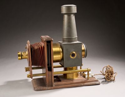 un petit appareil photo ancien posé sur un socle en bois et attaché par une corde