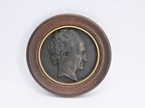 un portrait antique en bronze représentant une femme de profil sur fond blanc