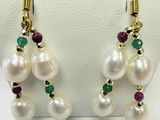 des boucles d'oreilles en perles blanches et émeraudes exposées dans une vitrine