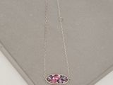 un gros plan d'un collier rose et violet posé sur une surface blanche