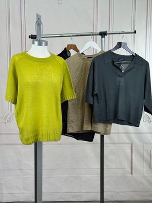 three sweaters hanging on a clothes rack in a room