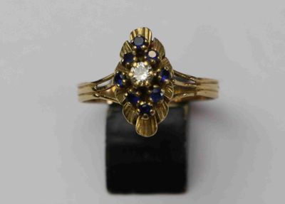 gros plan d'une bague en or avec des pierres bleues et blanches