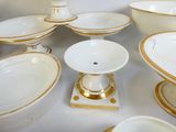 une multitude d'assiettes et de bols blancs et dorés posés sur une table