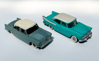 deux voitures jouets assises l'une à côté de l'autre sur une surface blanche