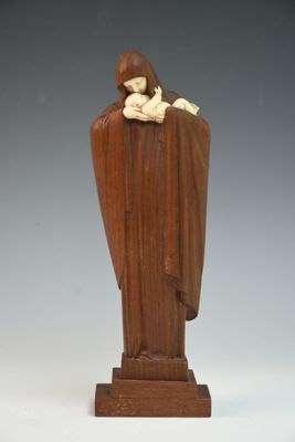 statue d'une femme tenant un enfant dans ses bras, posée sur un socle en bois