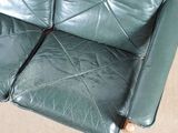 a cat sitting on a green leather couch in a living room