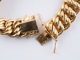 a gold chain bracelet with a lock on a white surface