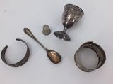 a silver cup, spoon, and other silver objects on a table