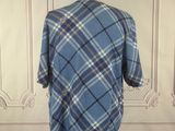blue plaid shirt on a mannequin stand in front of a white wall