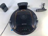 an image of a black and gold robot vacuum with a charger and other accessories
