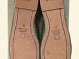 the bottom of a pair of green shoes with blue stitching