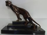 bronze statue of a dog on a black base on a white wall