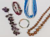 many different necklaces and bracelets laid out on a table