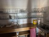 une cuisine équipée d'un évier et d'un plan de travail sur lequel sont posés des verres