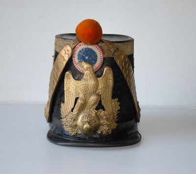 a black and gold vase with an orange on top