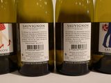 three bottles of white wine are lined up on a table