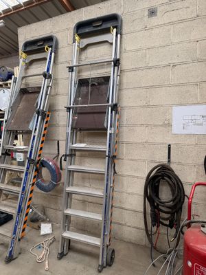 Plusieurs échelles sont alignées contre un mur dans un garage