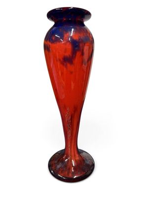 un vase rouge et bleu posé sur une surface blanche