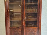 an old wooden cabinet with glass doors on top of it
