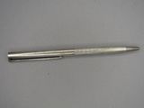 a silver pen sitting on top of a table next to a white surface