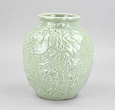 un vase vert posé sur une table, sur fond blanc