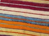 a close up of a colorful striped rug on a white surface