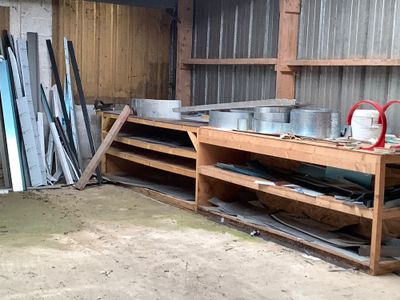 une étagère en bois sur laquelle sont posés des casseroles et des poêles, dans une remise